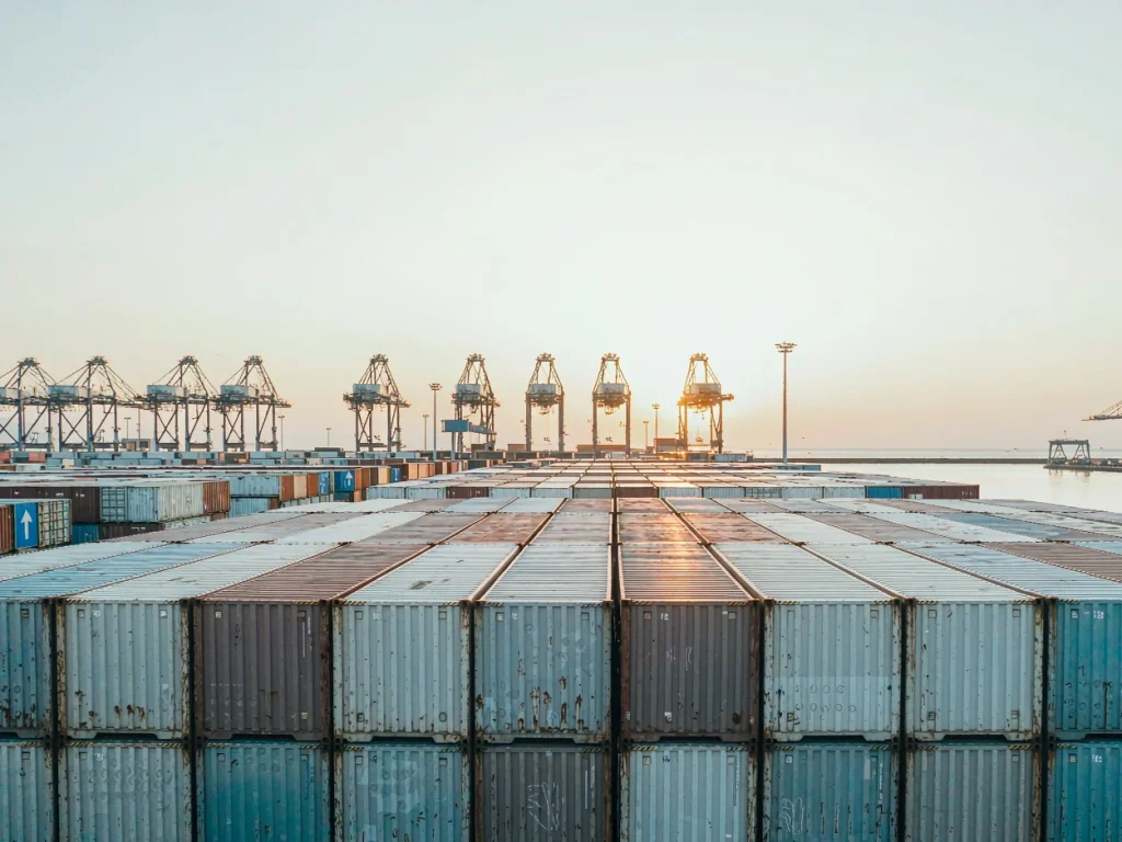 Stacked shipping containers at a seaport at dusk